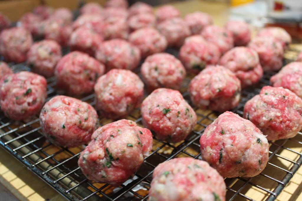 raw meatballs on grate