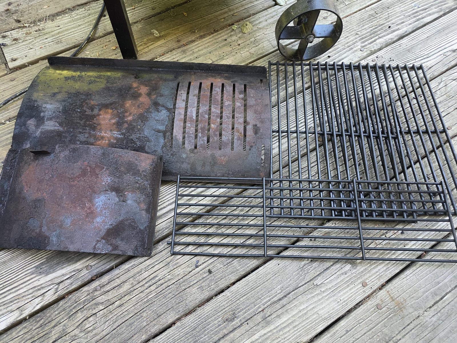 Cleaned Pit Boss flame broiler plates and cooking grates laid out on a deck