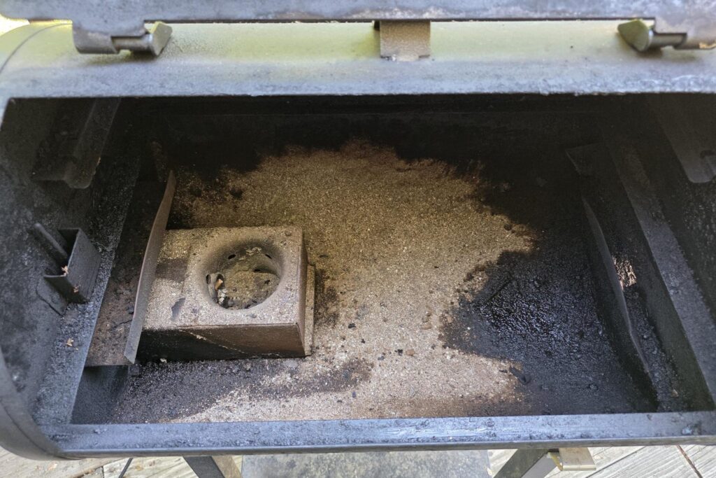 Inside a Pit Boss barrel showing ash buildup around the burn pot