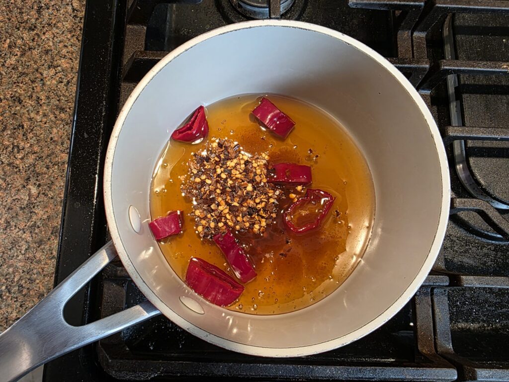 Honey, red pepper flakes and sliced cowhorn pepper in a saucepan before heating