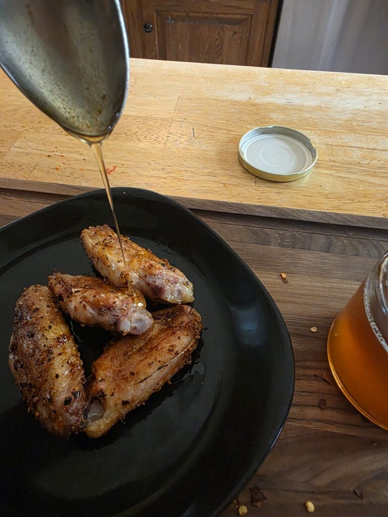 Hot honey pouring onto smoked chicken wings
