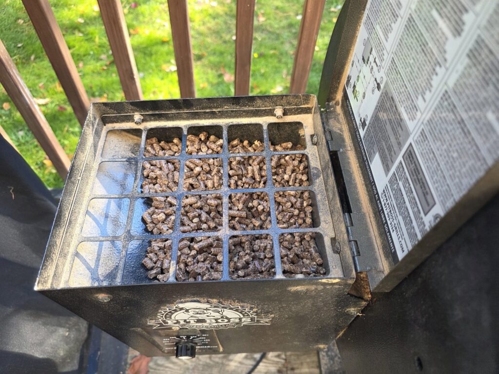 Open Pit Boss pellet hopper filled with wood pellets under the safety grate